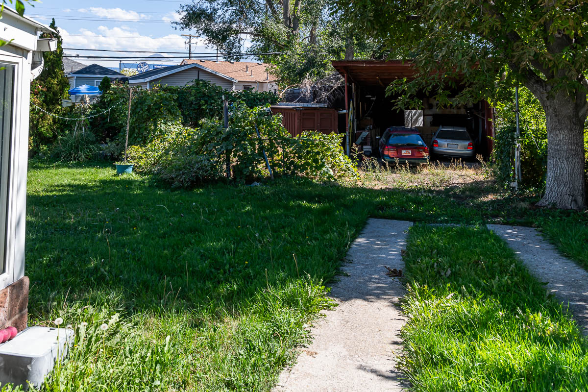messy back lot with old cars and carport before remodel